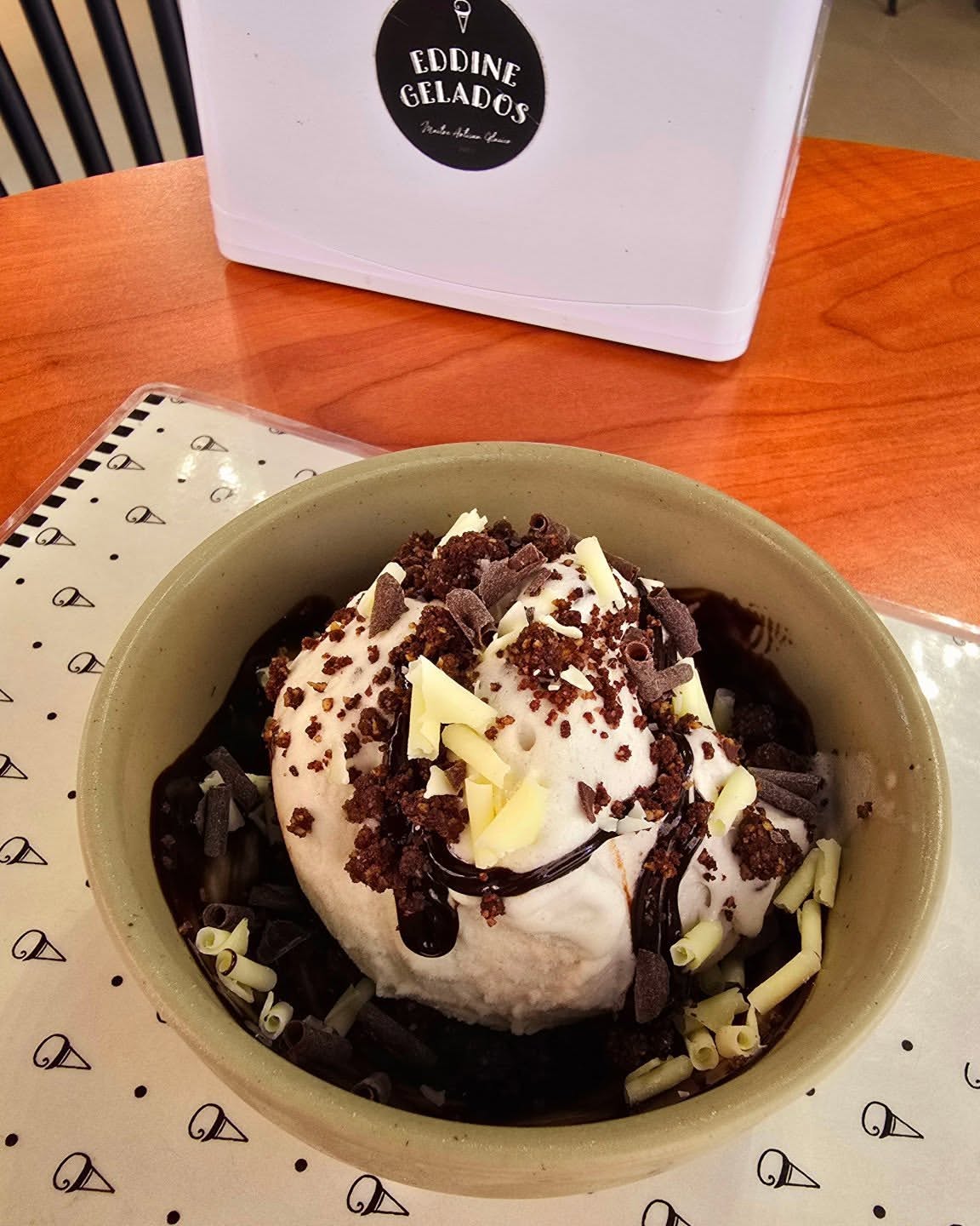 Gelado com calda de chocolate e biscoito numa taça